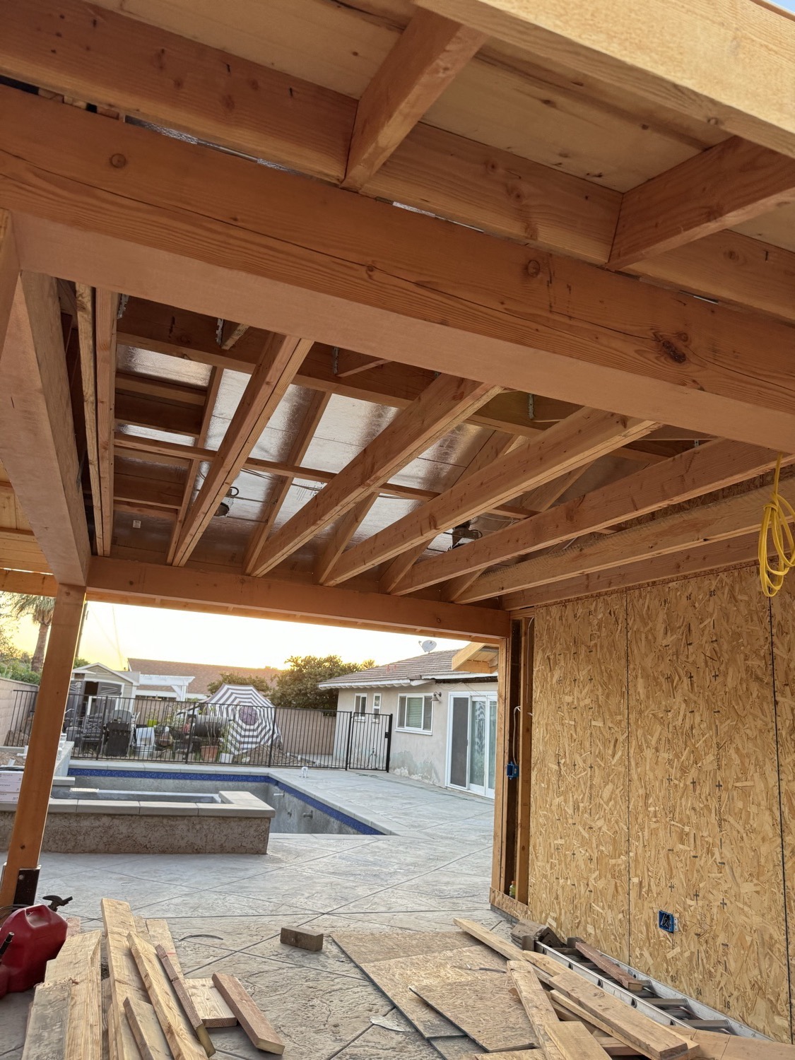 New custom patio cover construction overlooking a backyard pool