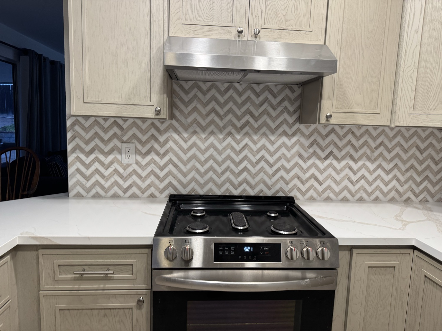 Finished kitchen with chevron marble backsplash and stainless range